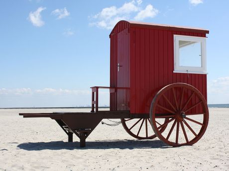 Eine rote Strandkarre steht auf dem Strand von Borkum, Südliches Ostfriesland